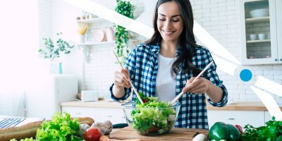 Woman fixing salad in kitchen